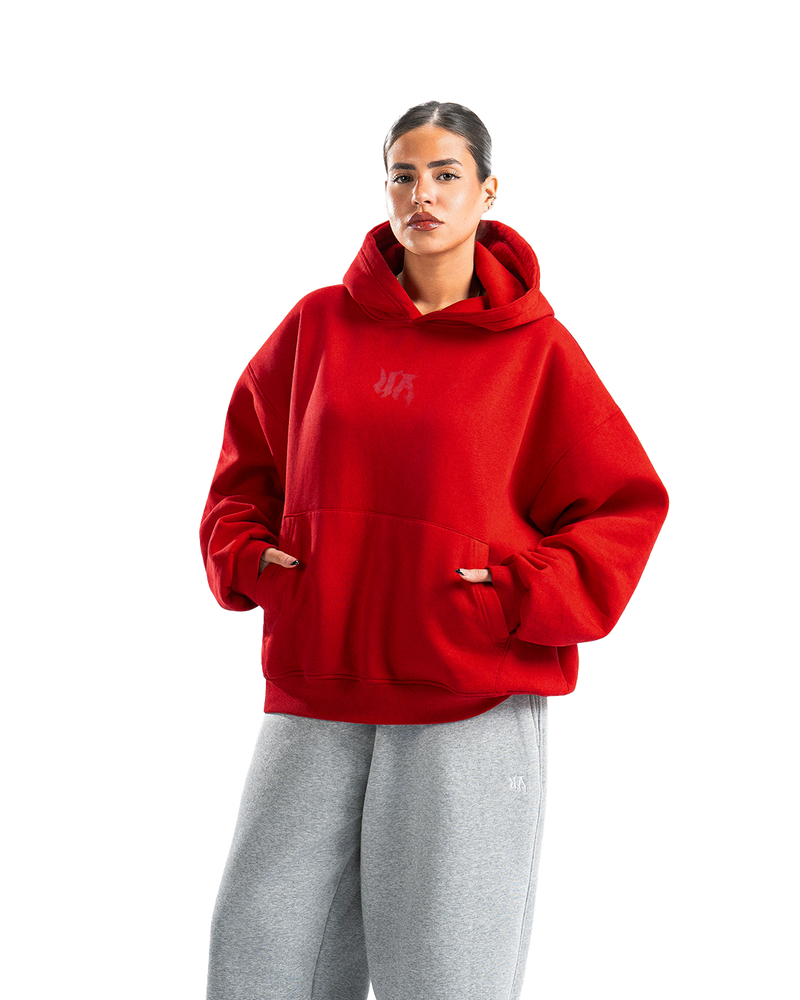 Person wearing a red hoodie with a graphic design on the back, standing against a white background