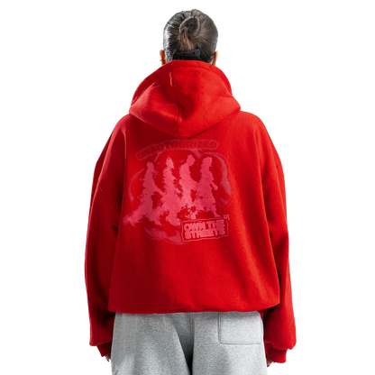 Person wearing a red hoodie with a graphic design on the back, standing against a white background